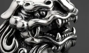 Detaljerad bild av en silverring med ett mytiskt väsen, kanske en drake eller lejon. Vad betyder ringa? Denna ring är ett konstverk.