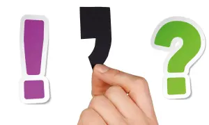 En hand håller ett svart semikolon mellan ett lila utropstecken och ett grönt frågetecken.