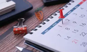 En kalender med en röd nål markerar en viktig dag. Planera dina månader på svenska med denna översikt.