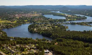 Vacker vy över en svensk stad vid en slingrande sjö. Hus och skog smälter samman, ett sant mannaminne.
