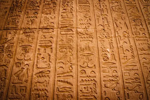 Detaljerade hieroglyfer på en stenmur. Varje symbol är mångfacetterad, berättar en historia från forntiden.