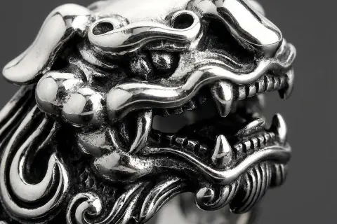 Detaljerad bild av en silverring med ett mytiskt väsen, kanske en drake eller lejon. Vad betyder ringa? Denna ring är ett konstverk.