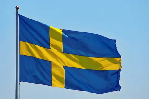 Sveriges flagga vajar i blå himmel. Kanske den viftar för att påminna oss om alla konstiga svenska ord som finns.