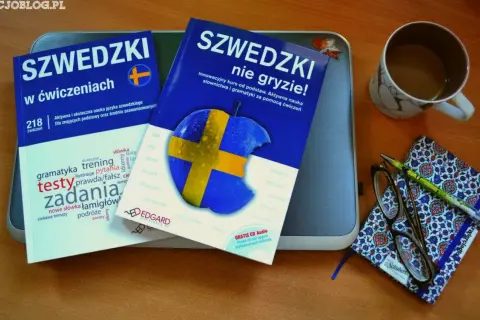 Två böcker om svenska språket, en kopp kaffe och en anteckningsbok med penna och glasögon. En perfekt uppsättning för den som vill lära sig språket, kanske som en andra person.