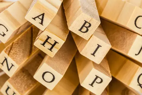 En hög med träklossar med bokstäver som A, B, C, G, H, I, J, N, O, P, Q. En snygg text att bygga ord med.