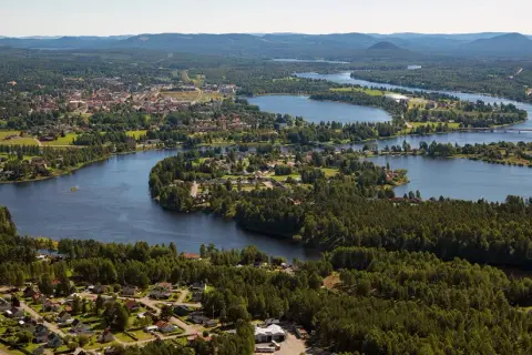Vacker vy över en svensk stad vid en slingrande sjö. Hus och skog smälter samman, ett sant mannaminne.