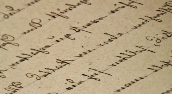 Detaljerad vy av handskriven text på gammalt papper. Texten är skriven med bläck och bildar rader som följer linjer. Det är svårt att tyda exakt vad som står, men det ger en känsla av ett gammalt referat.