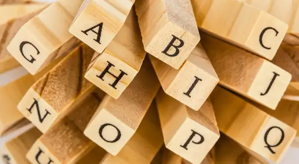 En hög med träklossar med bokstäver som A, B, C, G, H, I, J, N, O, P, Q. En snygg text att bygga ord med.