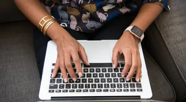 Person med kattmönstrad tröja och smycken skriver på en laptop. Ett resonerande text exempel på hur man kan beskriva en bild.