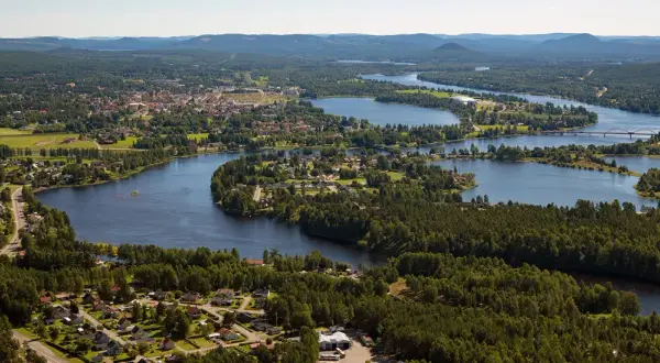 Vacker vy över en svensk stad vid en slingrande sjö. Hus och skog smälter samman, ett sant mannaminne.