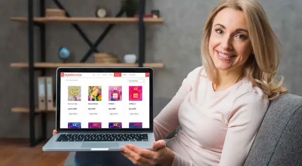 Glad kvinna visar sin laptop med en konst-webbshop. Hon bläddrar bland tavlor och parfymflaskor i webbshopen.