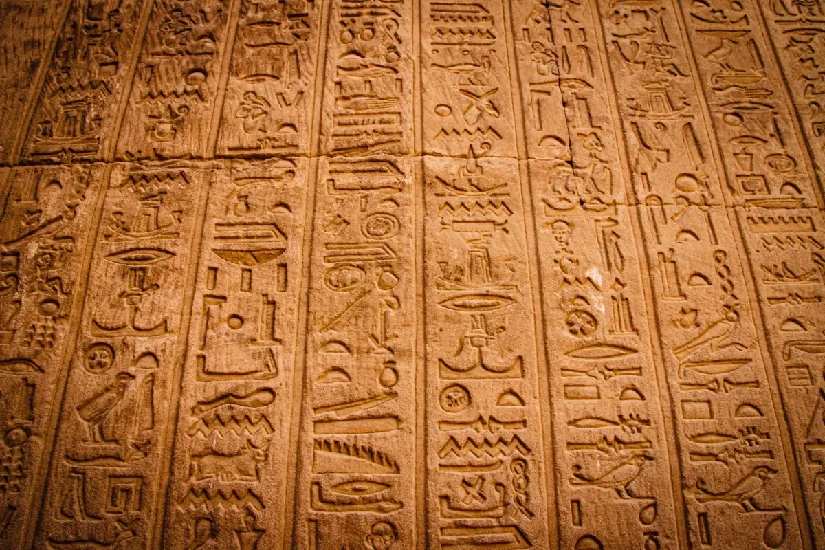 Detaljerade hieroglyfer på en stenmur. Varje symbol är mångfacetterad, berättar en historia från forntiden.