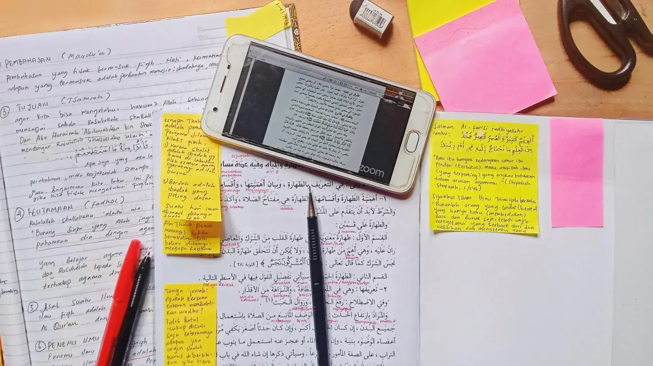 En mobiltelefon visar en text på arabiska, omgiven av anteckningar och post-it-lappar. En sammanfattning av uppsatsen kan finnas bland dessa.
