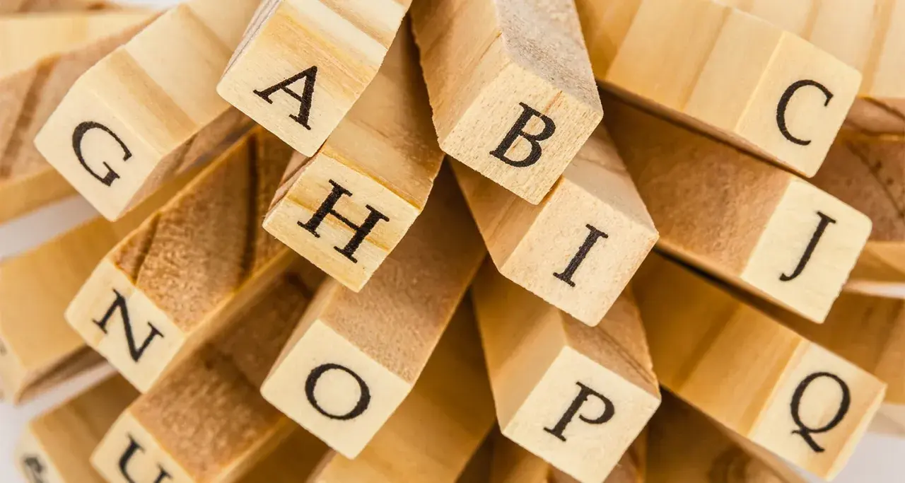 En hög med träklossar med bokstäver som A, B, C, G, H, I, J, N, O, P, Q. En snygg text att bygga ord med.