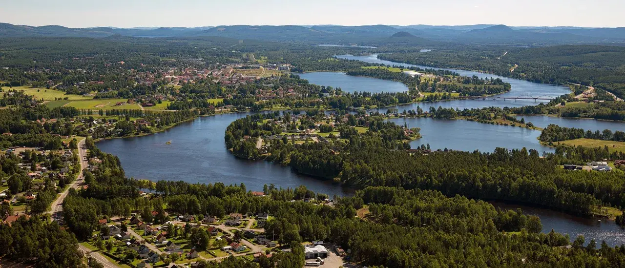 Vacker vy över en svensk stad vid en slingrande sjö. Hus och skog smälter samman, ett sant mannaminne.