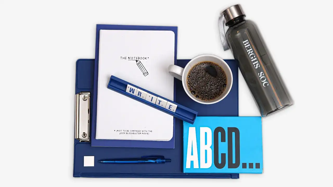 En anteckningsbok, kaffe och bokstäver som bildar "WRITE" förbereder för en argumenterande text.