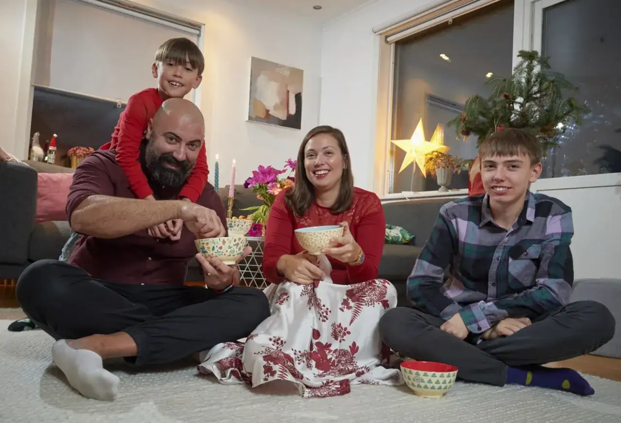 Familjen samlad f&ouml;r att fira jul. En pappa med son p&aring; axlarna, en mamma och en ton&aring;rsson sitter p&aring; golvet med sk&aring;lar. Detta &auml;r vad betyder jul.
